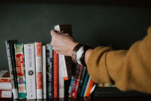 Hand choosing a book from a bookshelf