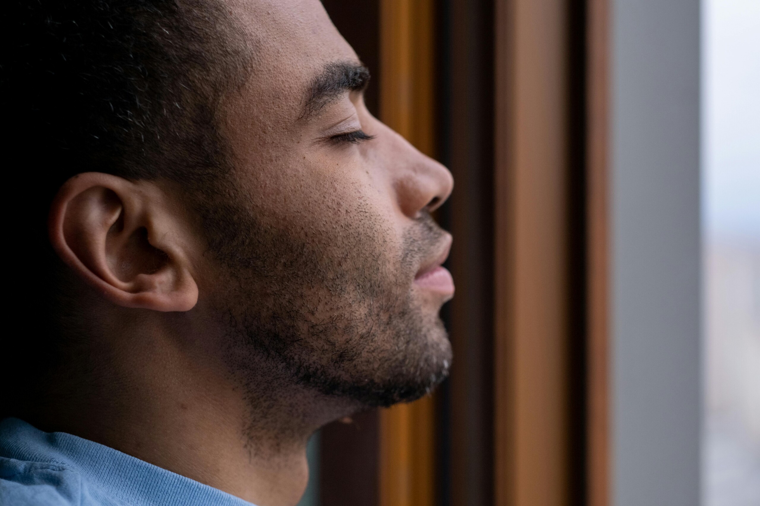 Man looking out of a window in soft daylight, seen in profile