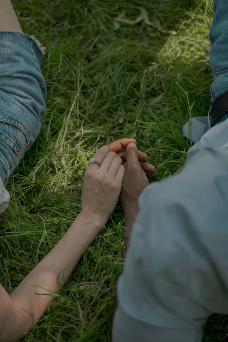 Two people sitting in the grass, holding hands