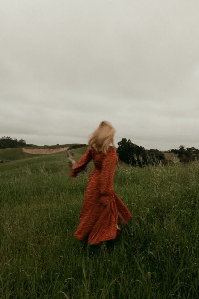 A woman walking through tall grass on an overcast day